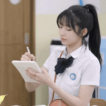 a girl in a school uniform is using a tablet