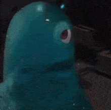 a blue cartoon character with a red eye is sitting on a table .