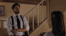 a man in suspenders stands next to a woman