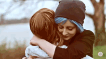 two women are hugging each other in a park .