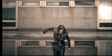 a woman in a suit is standing in front of a building that says ' eee ' on it