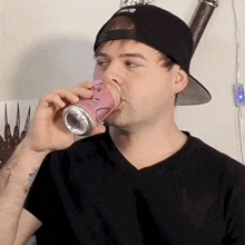 a man wearing a black hat is drinking from a can with a smiley face on it
