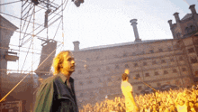 a man in a green jacket stands in front of a crowd of people