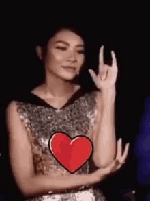 a woman in a sequined dress is making a devil horns sign with her hands