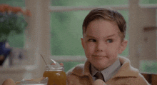 a young boy is sitting at a table with a jar of honey and eggs