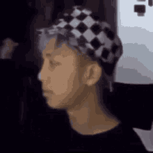 a man wearing a black and white checkered hat is looking at the camera .