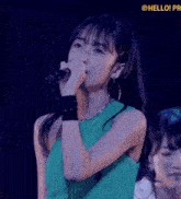 a woman in a green dress is singing into a microphone