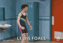 a man in a bathing suit is standing in a bathroom in front of lockers .