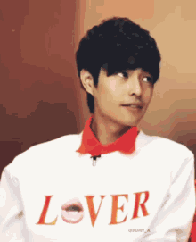 a young man wearing a white shirt that says lover