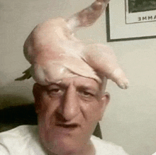 a man with a chicken on his head is taking a selfie .