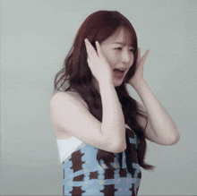 a woman in a plaid dress is covering her ears