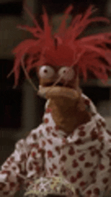 a puppet with red hair and glasses is wearing a pajama shirt and a hat .