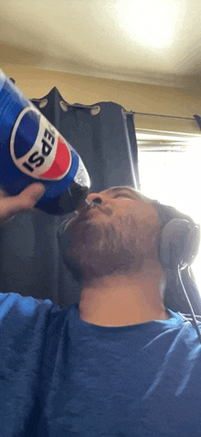 a man wearing headphones is drinking from a large pepsi bottle