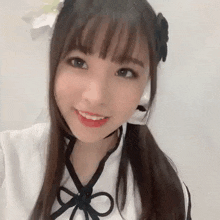a close up of a young girl wearing a white dress and a bow on her head .
