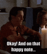 a man and a woman sit at a table with a candle and the words okay and on that happy note