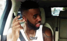 a man with a beard is sitting in a car and saying nice .