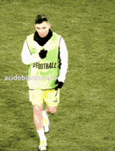 a soccer player wearing a green vest that says football
