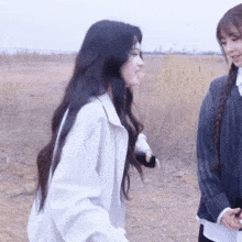 two girls are standing in a field one is wearing a white jacket and the other is wearing a black sweater