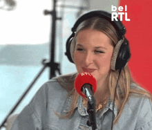a woman wearing headphones is smiling in front of a microphone that says rtl on it