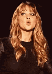 a woman with long blonde hair is making a face with her mouth open .