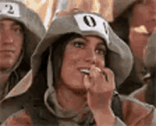 a woman wearing a hat with a number on it is sitting in a crowd of people .