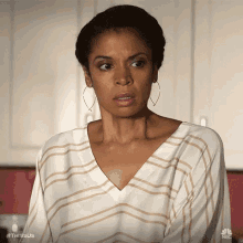 a woman wearing a striped shirt and hoop earrings is looking at the camera .