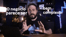 a man with a beard is sitting at a desk with the words bem complexo above him