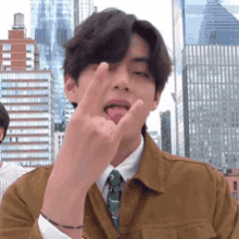 a man in a suit and tie is sticking his tongue out and making a rock sign .