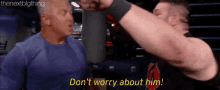 a man in a blue shirt is talking to another man in a wrestling ring .