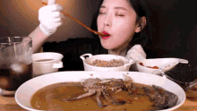 a woman is eating crab soup with chopsticks