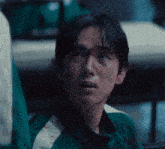 a man with blood on his face is wearing a green jersey