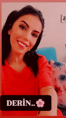 a woman in a red shirt is taking a selfie with the word derin on the bottom right