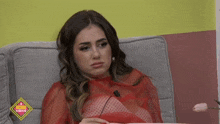 a woman in a red top sits on a couch in front of a sign that says ' el diario '