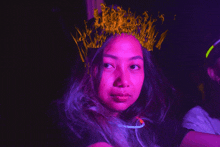 a woman with a crown on her head is surrounded by purple and yellow lights