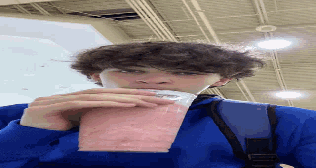 a young boy in a blue sweatshirt drinks a pink smoothie