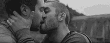 a black and white photo of two men kissing .