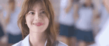 a young woman in a white shirt is smiling in a classroom with other students .