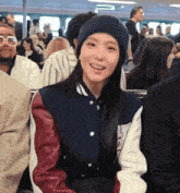 a woman wearing a beanie and a jacket is smiling in a crowd