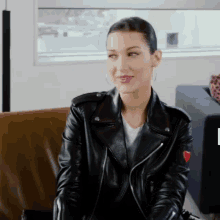 a woman wearing a leather jacket is sitting on a couch .