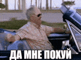 a man wearing sunglasses is sitting in a car with a caption in russian that says " da mne poxyy "