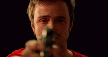a man is pointing a gun at the camera in a close up .