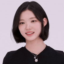 a young woman wearing a black shirt and a necklace with a smiley face on it