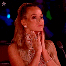 a woman sitting in front of a microphone with her hands on her face ..