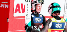 two skiers are standing in front of a sign that says av