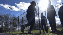 a group of people standing behind a fence with the sun shining through it