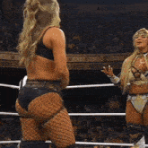 two women wrestling in a ring with a crowd in the background