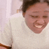 a woman in a white shirt is smiling and looking down .