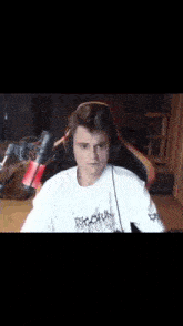 a man wearing headphones and a white shirt is talking into a microphone .