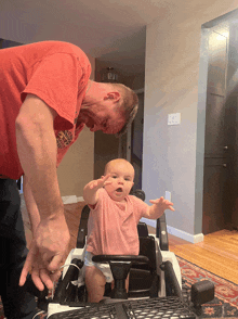 a man in a red shirt is holding a baby in a toy car