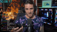 a man wearing headphones holds a microphone in front of a screen that says 30 08 17